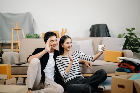 Photo for Asian young attractive couple man and woman using smartphone for online shopping in new house. Young married asian moving home. - Royalty Free Image