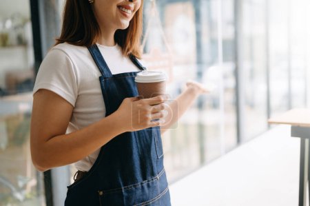Téléchargez les photos : Jeune femme asiatique propriétaire de café prêt à recevoir des commandes dans le restaurant du café. femme barista café - en image libre de droit