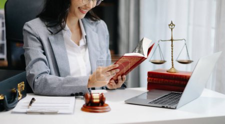 Rechtsanwältin liest Rechtsbuch mit Hammer auf dem Tisch im Büro. Justiz und Recht, Rechtsanwaltskonzept