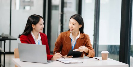 Photo for Two Asian businesswomen discuss investment project working and planning strategy with laptop computer in office - Royalty Free Image