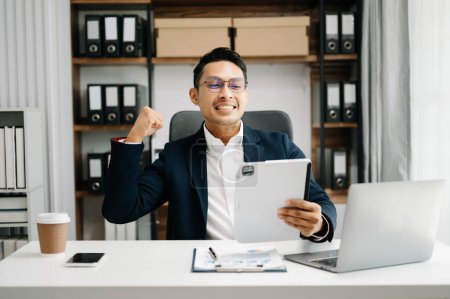 Foto de Joven asiático trabajador de oficina en traje de negocios trabajando y sonriendo en la oficina - Imagen libre de derechos