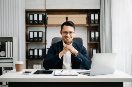 Foto de Joven asiático trabajador de oficina en traje de negocios trabajando y sonriendo en la oficina - Imagen libre de derechos