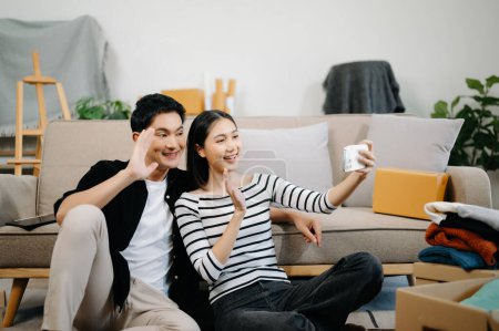 Photo for Asian young attractive couple man and woman using smartphone for online shopping in new house. Young married asian moving home. - Royalty Free Image