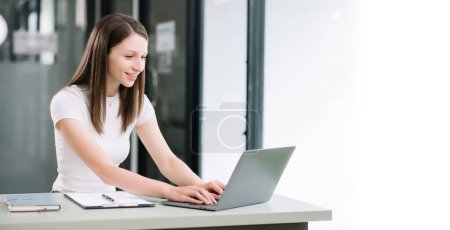 Téléchargez les photos : Femme confiante utilisant un ordinateur portable au bureau moderne - en image libre de droit