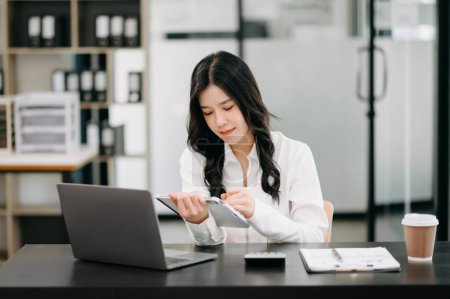 Photo for Successful Asian Businesswoman Analyzing Finance on digital tablet at modern Office Desk tax, report, accounting, statistics, and analytical research concept - Royalty Free Image