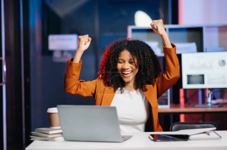 Téléchargez les photos : Femme d'affaires sont ravis et heureux avec le travail sur ordinateur portable au bureau. lumière au néon dans le temps sombre - en image libre de droit