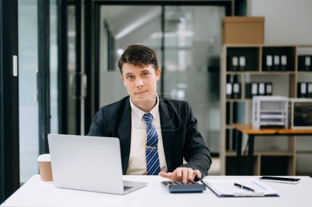 Téléchargez les photos : Jeune homme d'affaires travaillant au bureau avec ordinateur portable - en image libre de droit