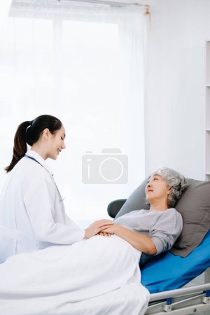 Téléchargez les photos : Asiatique médecin en costume blanc examen asiatique femme âgée patient qui est couché sur le lit à l'hôpital - en image libre de droit