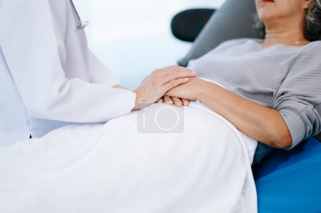 Photo for Asian doctor in white suit examining Asian elderly woman patient who is lying on bed in hospital - Royalty Free Image