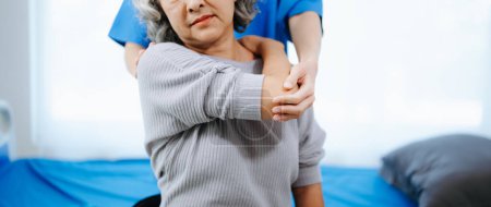 Foto de Fisioterapeuta asiática ayudando a paciente femenina a estirar el brazo durante el ejercicio en la oficina del hospital - Imagen libre de derechos