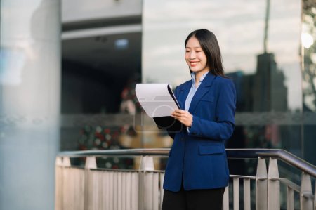 Téléchargez les photos : Heureuse femme d'affaires asiatique travaillant avec des documents dans la rue de la ville - en image libre de droit