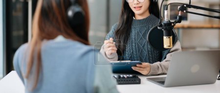 Junge Frauen mit Kopfhörern machen einen Live-Podcast für ihren Sender, Kommunikation für Radio-Podcast, Technologiekonzept