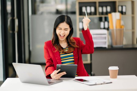 Téléchargez les photos : Asiatique femme d'affaires heureux avec le travail sur tablette numérique au bureau - en image libre de droit