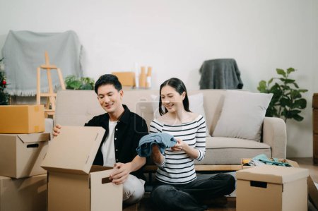 Téléchargez les photos : Jeune couple avec de grandes boîtes emménageant dans une nouvelle maison. heureux asiatique l'homme et la femme dans maison intérieur - en image libre de droit