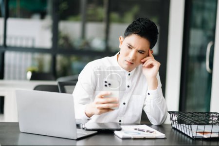 Téléchargez les photos : Asiatique homme d'affaires est stressé et ennuyé de travailler dans un bureau moderne - en image libre de droit