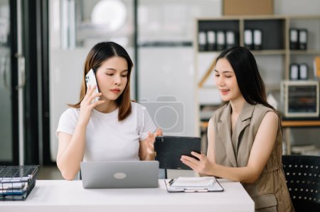 Téléchargez les photos : Deux femmes d'affaires asiatiques discutent de la stratégie de travail et de planification du projet d'investissement dans un bureau moderne. - en image libre de droit