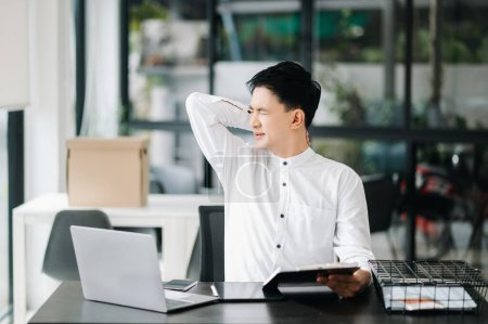 Foto de Empresario asiático está estresado, aburrido, y pensando en exceso de trabajar en la oficina moderna - Imagen libre de derechos