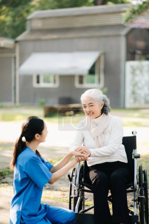 Photo for Young Asian taking care of senior woman on wheelchair in hospital park. Senior healthcare concept - Royalty Free Image