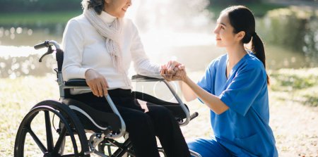 Photo for Young Asian taking care of senior woman on wheelchair in hospital park. Senior healthcare concept - Royalty Free Image