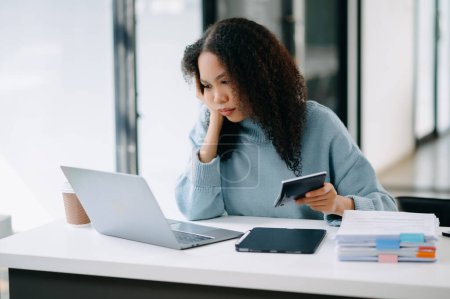 Téléchargez les photos : Femme d'affaires est stressée, ennuyée et trop réfléchie de travailler sur une tablette au bureau moderne - en image libre de droit