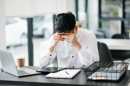 Foto de Empresario asiático está estresado, aburrido, y pensando en exceso de trabajar en la oficina moderna - Imagen libre de derechos