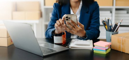 Téléchargez les photos : Jeune femme tenant un smartphone en utilisant pour le paiement, comme concept d'achat en ligne dans le bureau - en image libre de droit