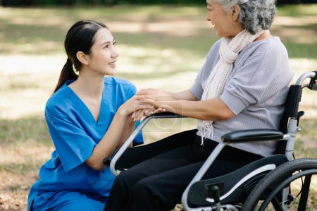Photo for Elderly asian senior woman on wheelchair with Asian careful caregiver and encourage patient in garden. with care from a caregiver and senior health insurance - Royalty Free Image