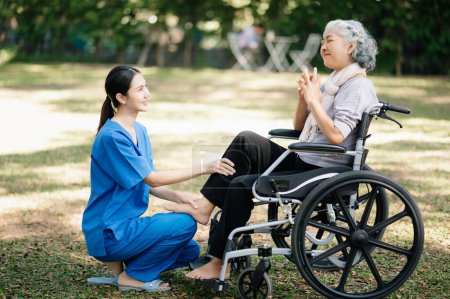 Photo for Asian physiotherapist helping elderly woman exercising in the garden - Royalty Free Image