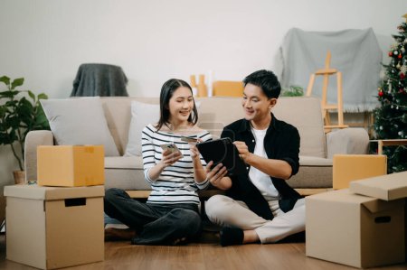Photo for Asian young attractive couple man and woman use smartphone and tablet  for online shopping furniture to decorate house in new house - Royalty Free Image