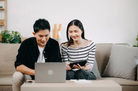 Photo for Asian young attractive couple man and woman use laptop for online shopping furniture to decorate new house - Royalty Free Image