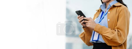 Photo for Confident Asian woman with standing on the street at outside office. Businesswoman using smartphone with business center on the background - Royalty Free Image