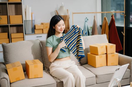 Foto de Concepto de blogger de moda, Mujer joven asiática vendiendo ropa en video streaming.Startup PYME pequeña empresa, usando tableta - Imagen libre de derechos