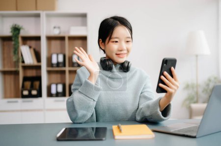 Téléchargez les photos : Femme asiatique en utilisant le smartphone et la tablette à la maison - en image libre de droit
