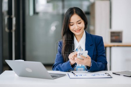 Photo for Beautiful Asian business woman working on laptop and using smartphone, Placed at the table at the office - Royalty Free Image