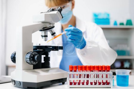 Foto de Científica femenina que trabaja con micropipetas analizando muestras bioquímicas, laboratorio químico de ciencia avanzada para la medicina. - Imagen libre de derechos
