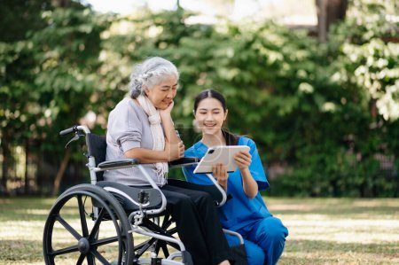 Foto de Anciano asiático senior mujer en silla de ruedas con cuidadoso cuidador en jardín - Imagen libre de derechos