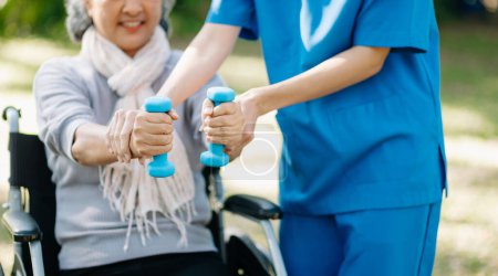 Téléchargez les photos : Asiatique physiothérapeute aider femme âgée exercer les mains dans le jardin - en image libre de droit