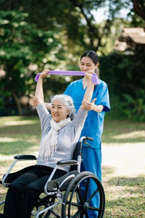 Asiatische Physiotherapeutin hilft älteren Frauen beim Händewaschen im Garten