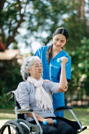 Photo for Asian physiotherapist helping elderly woman exercising hands in the garden - Royalty Free Image