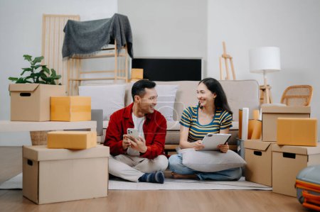 Asiatische junge attraktive Paar Mann und Frau verwenden Smartphone und Tablet für Online-Shopping-Möbel, um Haus zu dekorieren