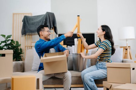 Téléchargez les photos : Heureux asiatique jeune attrayant couple homme et femme avec de grandes boîtes de déménagement dans une nouvelle maison - en image libre de droit