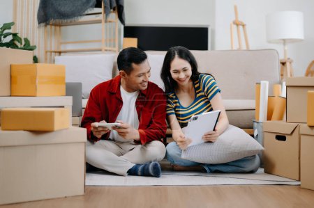 Photo for Asian young attractive couple man and woman use smartphone and tablet  for online shopping furniture to decorate  house - Royalty Free Image