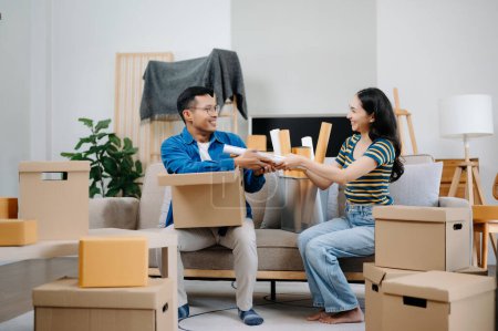 Heureux asiatique jeune attrayant couple homme et femme avec de grandes boîtes de déménagement dans une nouvelle maison
