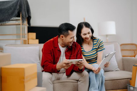 Téléchargez les photos : Asiatique jeune couple attrayant homme et femme utiliser smartphone et tablette pour les meubles de magasinage en ligne pour décorer nouvelle maison - en image libre de droit
