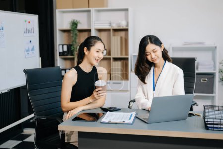 Téléchargez les photos : Deux femmes d'affaires asiatiques discutent du projet d'investissement, de la stratégie de travail et de planification avec ordinateur portable dans un bureau moderne - en image libre de droit