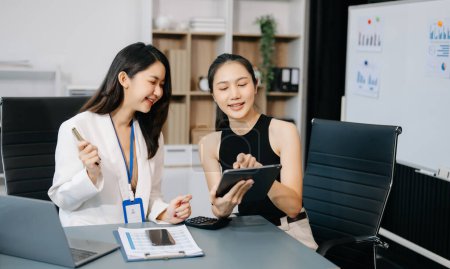 Photo for Businesswomen work and discuss their business plans. A woman employee explains and shows her colleague the results in modern office - Royalty Free Image