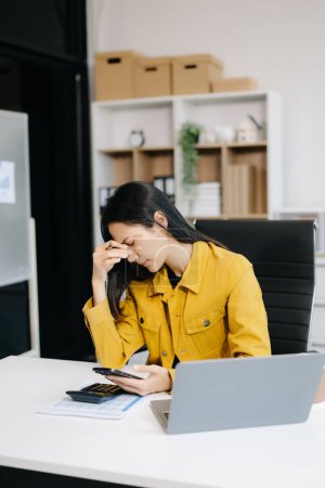Photo for Young beautiful woman work late in the office.  Upset businesswoman bending over workplace while looking at smartphone - Royalty Free Image