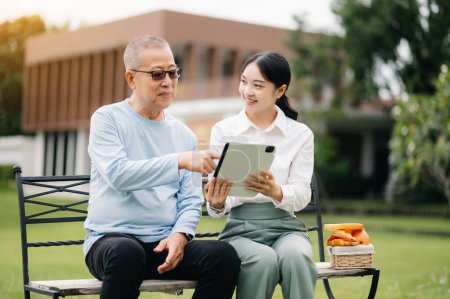 Anciano asiático senior hombre en silla de ruedas con asiática cuidadoso cuidador con tableta pc y comida en hospital jardín concepto.