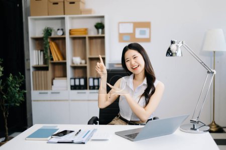 Foto de Joven atractivo asiático mujer oficina trabajador negocio sonriendo y el uso de ordenador portátil en la oficina moderna - Imagen libre de derechos
