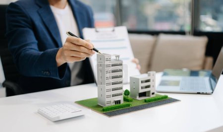 Makler stellt Modell für Eigenheime vor. Geschäftsmann berät Kunden über Hypothekenkreditangebot im Amt 
